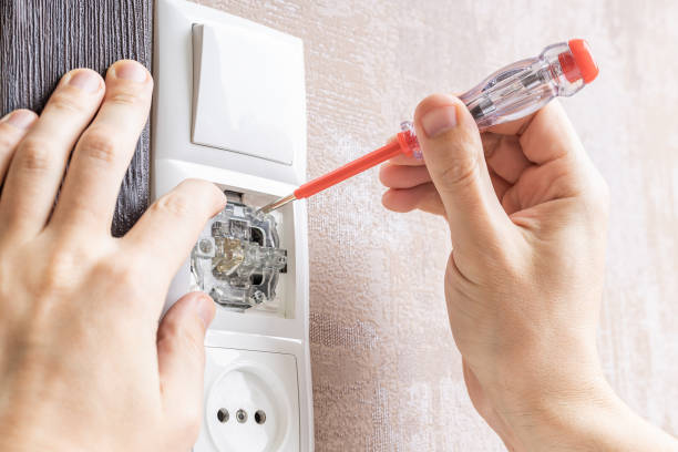 handyman repair wall light switch at apartment. worker using voltage electric tester pen to check power switch. electrician service concept.